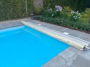 a blue swimming pool next to a garden with flowers at Flat vane & Soun in Waterloo
