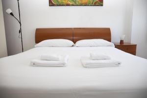 Una cama blanca con dos toallas blancas. en Astri Apartment, en Roma
