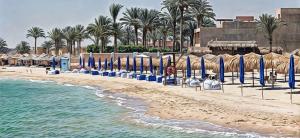 a beach with blue umbrellas and the ocean at شاليه قرية المنال ٢ in Ain Sokhna