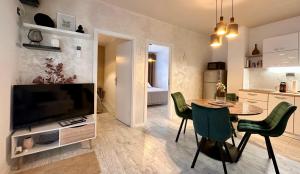 a living room with a table and a television and a kitchen at Apartments Sinisa - Krk Town in Krk