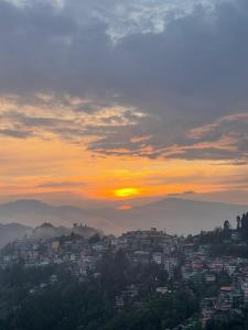 una vista de una ciudad con la puesta de sol en el fondo en Tigerhill Homestay, en Darjeeling