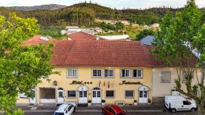 a yellow building with cars parked in front of it at Hotel Ulveira in Oliveira de Frades