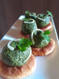 une plaque contenant quatre beignets avec un pesto vert sur eux; dans l'établissement Guest house Nano, à Martvili