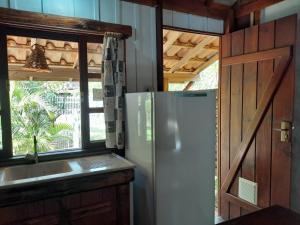 een keuken met een koelkast, een wastafel en een raam bij Recanto das Bromélias Chalés in Guarda do Embaú