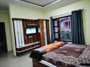 een slaapkamer met een bed en een raam met een televisie bij Galaxy Inn Homestay in Banikhet