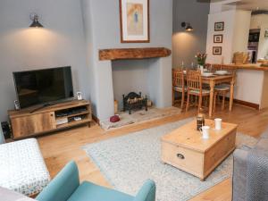 a living room with a television and a table and chairs at Bumble Cottage in Holmfirth