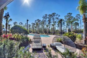 - une piscine de style complexe avec 2 chaises et des palmiers dans l'établissement Spacious 3BR Condo with Pool & Hot Tub near Disney, à Orlando