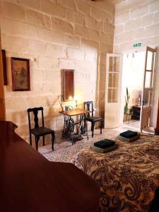 Habitación con mesa, sillas y pared de piedra. en Charming House in Victoria, Gozo, en Victoria