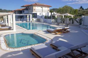 una piscina con tumbonas y una casa en Ampelia Hotel Kassandra, en Chaniotis