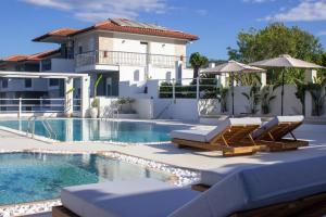 einen Pool mit zwei Liegestühlen und ein Haus in der Unterkunft Ampelia Hotel Kassandra in Chaniotis