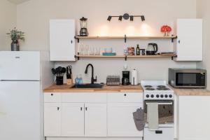a white kitchen with white cabinets and a sink at Cozy Studio Apt Close to the Gardens - King Bed in Huntsville