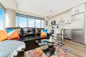 a living room with a black leather couch and a kitchen at Newly Built Condo w Amazing Amenities and Views in Kitchener