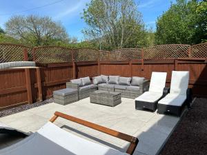 a patio with a couch and two chairs at Honeycott in Crickhowell