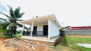 a white house with a porch and a palm tree at Kihansa Villa in Kalutara