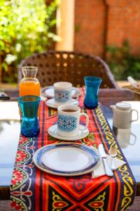 Dar Lina Guesthouse Luxor في الأقصر: طاولة مع أطباق وأكواب من القهوة والعصير
