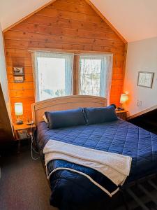 a bedroom with a blue bed in a room with wooden walls at The Shepherd's Retreat in Livingston