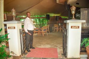 a man standing between two pillars in a room at Desert Rose Resort Kisumu in Kisumu