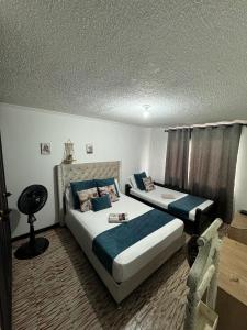 1 dormitorio con 2 camas y almohadas azules en coliving el jardin de envigado sede san marcos, en Envigado