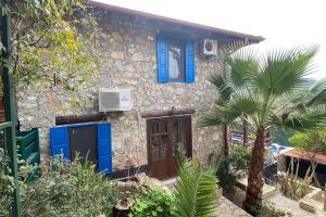 a stone house with blue doors and a palm tree at Orman İçinde Muhteşem Villa in Kayakoy