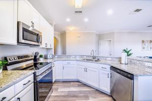 a kitchen with white cabinets and stainless steel appliances at Cozy 2BR Condo - Private Balcony - Near Disney in Orlando
