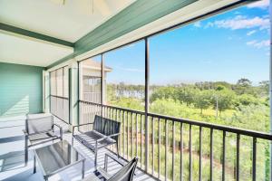 a balcony with chairs and a view of the woods at Bright Condo - 2BR with Pool & Hot Tub, near Disney! in Orlando