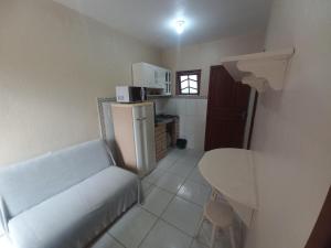 a small kitchen with a couch and a refrigerator at Pousada Belas Praia quarto Praia da Vila in Imbituba