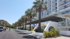 une rue bordée de palmiers en face d'un bâtiment dans l'établissement Vilamoura Dream House QR2, à Quarteira