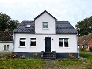 une maison blanche avec un toit noir dans l'établissement Landhaus-Ferienwohnung am Fluss, à Plattenburg