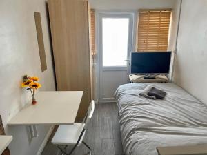 um pequeno quarto com uma cama, uma secretária e uma televisão em Rooms at EEJ homes em Londres