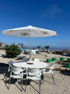 a white table and chairs under an umbrella on the beach at Casa Rural El Pasil 2 in Arona
