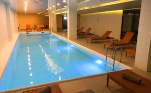 una gran piscina en un edificio con mesas y sillas en The Valley Residence & Spa SUITE 223, en Bakuriani