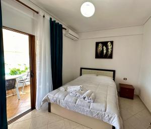 a bedroom with a bed and a large window at SHEMO Apartments in Sarandë