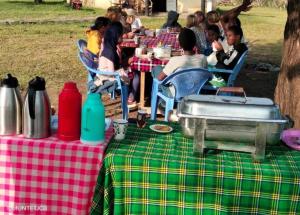 a group of people sitting at a picnic table at Emayian sekenani camp in Sekenani