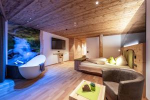 a hotel room with a tub and a bed at Moarlhof - Farm Nature Resort in Castelrotto +59 photos
