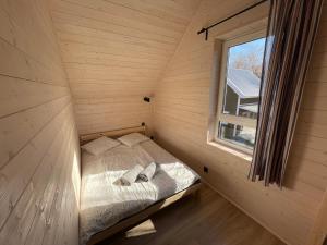 een bed in een kleine kamer met een raam bij FOLGI - Domki Jeżowa in Kopalino