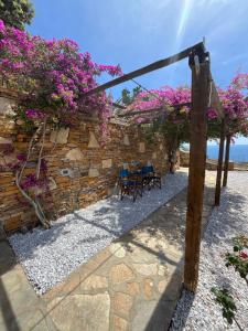 un patio con flores púrpuras y una pared de piedra en SerenSea Bliss, Naousa, Kythnos en Kíthnos