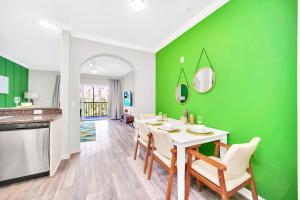 a kitchen and dining room with a green wall at Modern 3BR Condo Near Disney- Pool and Hot Tub in Orlando
