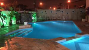een zwembad 's nachts met lichten aan bij Pousada D'Ibiza - Itanhaém in Itanhaém
