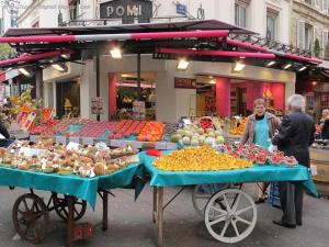 two people standing in front of a market with fruits and vegetables at Branded New Cozy Studio in the Heart of Paris 17 in Paris +9 photos