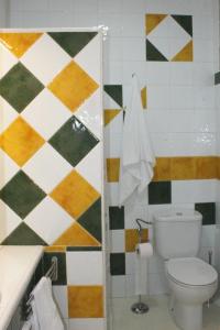 a bathroom with a toilet and a checkerboard wall at Apartamento La esquina del Castillo in Caravaca de la Cruz +7 photos