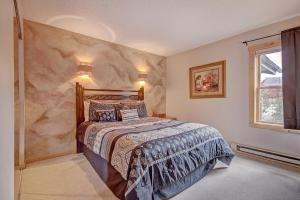 1 dormitorio con cama y pared de piedra en Sawmill Creek Condo 309 by Great Western Lodging en Breckenridge