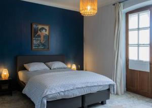 a bedroom with a bed with a blue wall at Villa CARAMEL - Piscine - VUE in Fargues +33 photos