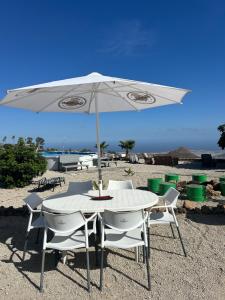 a white table and chairs under an umbrella on the beach at Casa Rural El Pasil in Arona