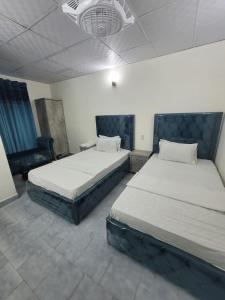 Un dormitorio con 2 camas y una silla. en Blue diamond guest house en Karachi