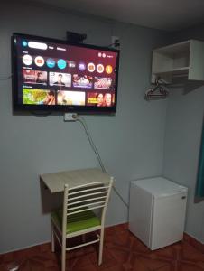 a tv on a wall with a chair and a table at Hostal El Pilar in Lima