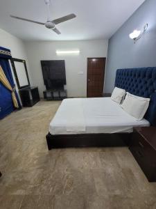 1 dormitorio con 1 cama grande y cabecero azul en Blue diamond guest house en Karachi
