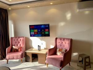 Porto Said Resort Chalet في بورسعيد: كرسيان ورديان وطاولة في الغرفة