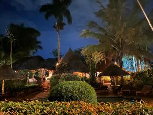 a resort with a pool and palm trees at night at Afro Smile Hotel and Guest House in Jinja