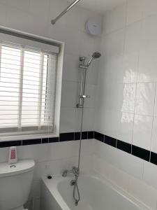 La salle de bains est pourvue d'une douche, de toilettes et d'une baignoire. dans l'établissement Sandra Stay MP, à Londres