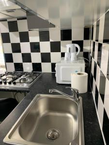 a kitchen with a sink and a checkered wall at Sandra Stay MP in London